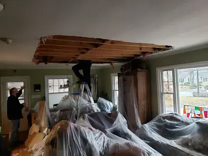 Crew working on a ceiling opened above plastic-covered furniture after a Kernersville roof leak