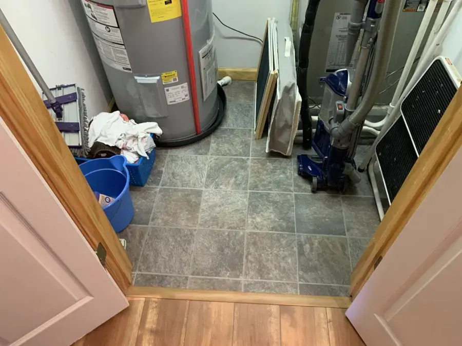 Water heater closet with towels and a bucket on the tile floor after a tank leak in Kernersville